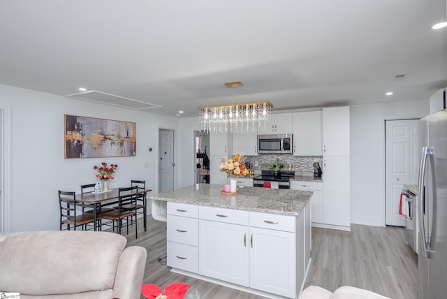 kitchen with stainless steel appliances, light wood-type flooring, white cabinetry, and tasteful backsplash