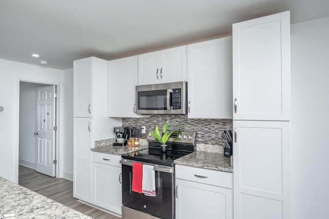 kitchen with stainless steel appliances, white cabinets, backsplash, and light stone countertops