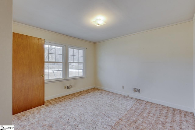 spare room with ornamental molding, carpet, visible vents, and baseboards