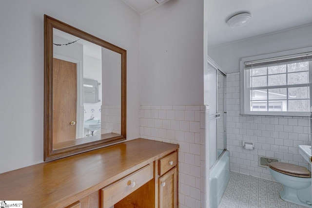 full bath featuring toilet, bath / shower combo with glass door, tile walls, and tile patterned floors