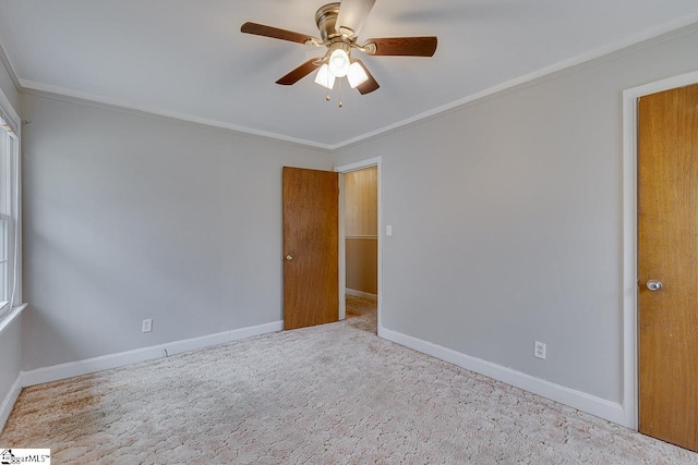 carpeted empty room with crown molding, a ceiling fan, and baseboards