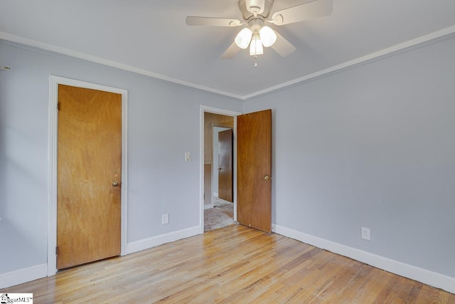 empty room with wood finished floors, a ceiling fan, and baseboards