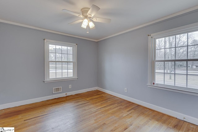 empty room featuring baseboards, crown molding, visible vents, and light wood finished floors