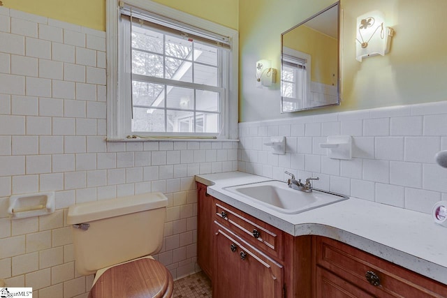 half bath featuring toilet, wainscoting, tile walls, and vanity