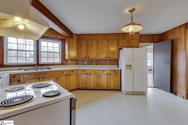 kitchen with light countertops, white appliances, a sink, and wooden walls