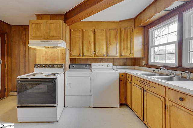 kitchen featuring under cabinet range hood, wood walls, a sink, independent washer and dryer, and white range with electric stovetop