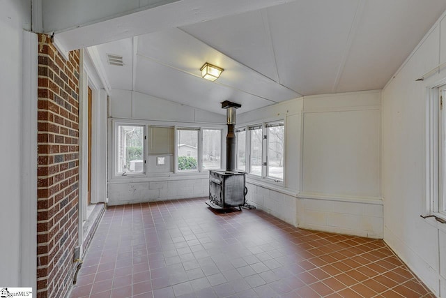 unfurnished sunroom with a wood stove, visible vents, and vaulted ceiling