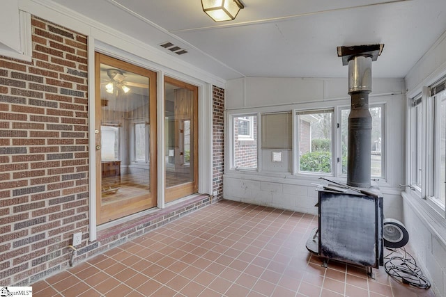 unfurnished sunroom with a wood stove and visible vents