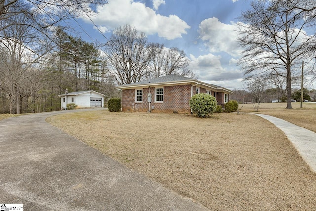 view of front of property with an outbuilding, a garage, brick siding, crawl space, and a front yard