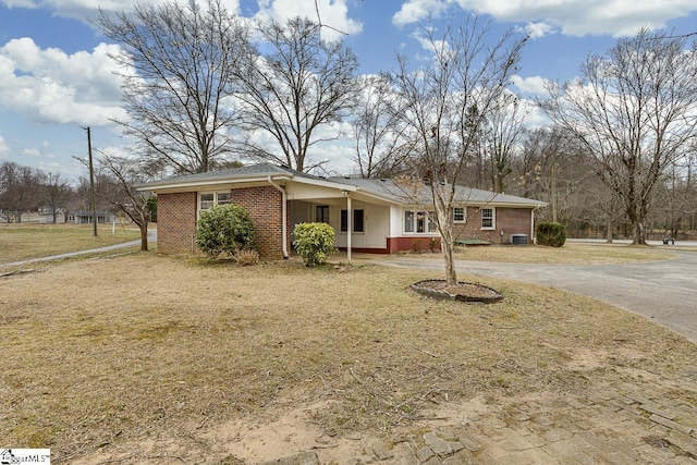 ranch-style house with aphalt driveway, a front yard, and brick siding