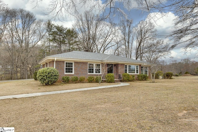 ranch-style home featuring brick siding, a front lawn, and roof with shingles