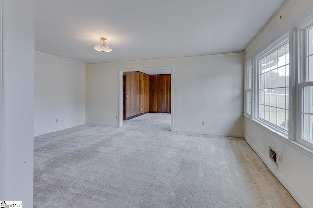 empty room with light colored carpet, crown molding, visible vents, and baseboards