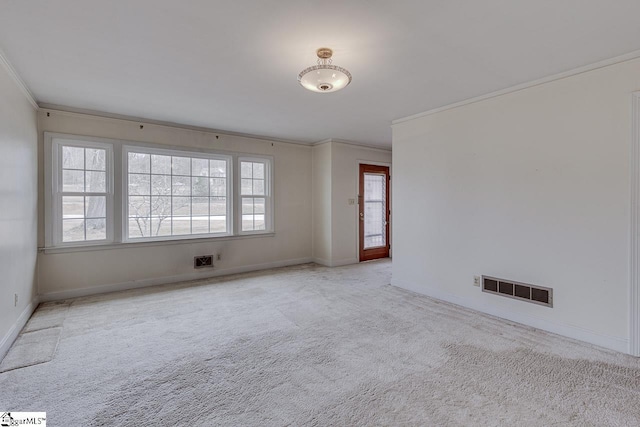 empty room with ornamental molding, carpet flooring, visible vents, and baseboards