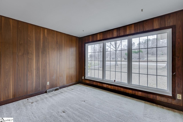 carpeted empty room with visible vents and wooden walls