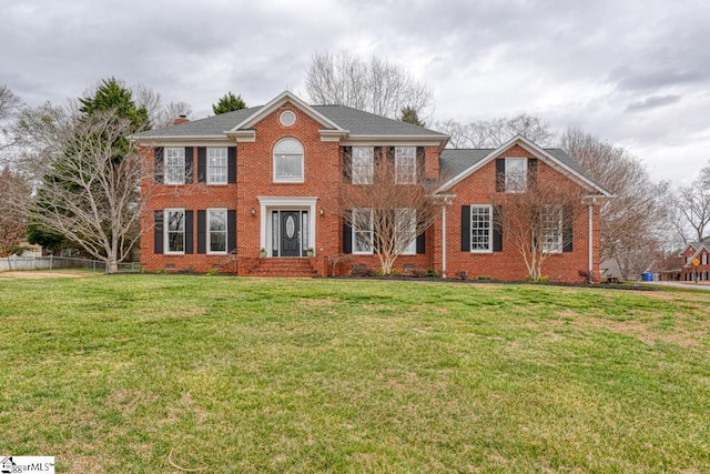 colonial inspired home featuring brick siding, fence, crawl space, a front lawn, and a chimney