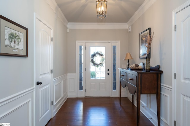 entryway with dark wood-type flooring, a wainscoted wall, ornamental molding, and a decorative wall