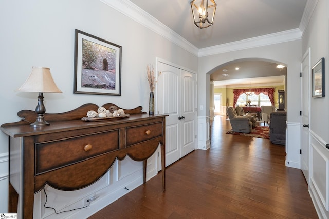 entryway featuring a chandelier, arched walkways, ornamental molding, and wood finished floors