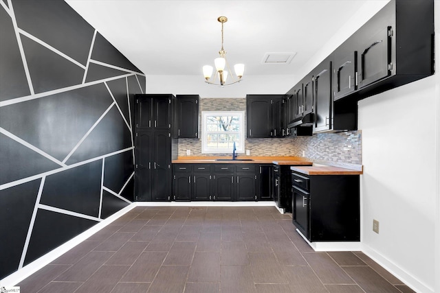 kitchen with butcher block counters, dark cabinetry, a sink, and decorative backsplash