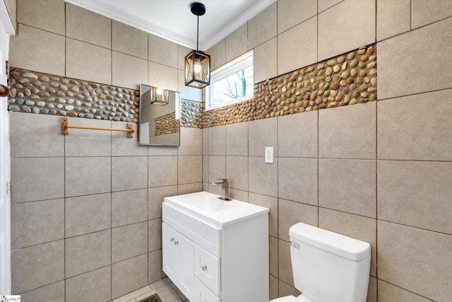 bathroom featuring tile walls, crown molding, vanity, and toilet