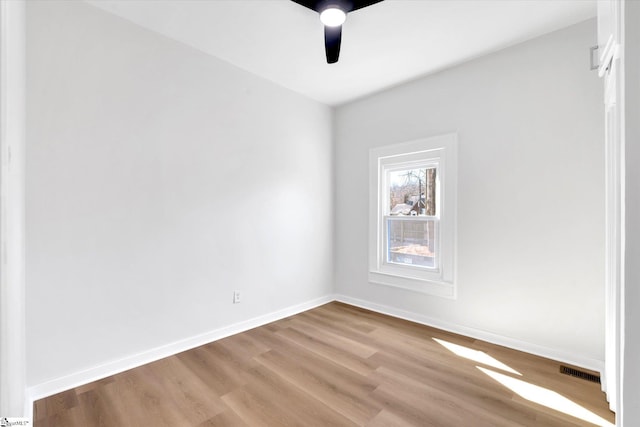 spare room featuring baseboards, visible vents, ceiling fan, and wood finished floors