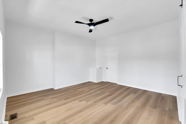 empty room featuring a ceiling fan, visible vents, light wood-style flooring, and baseboards