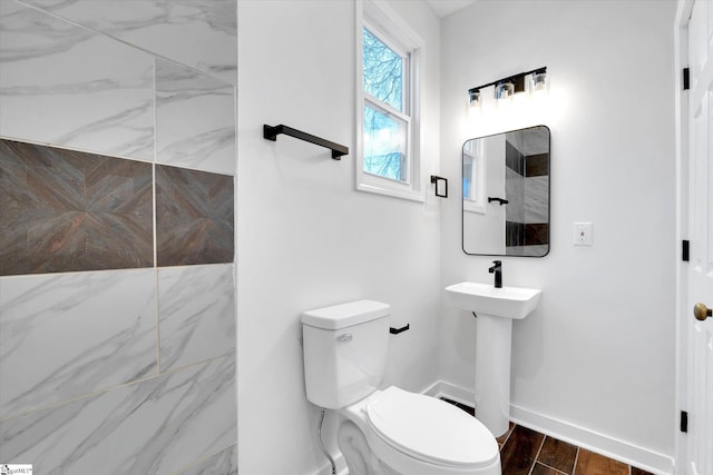 bathroom with wood finished floors, toilet, and baseboards