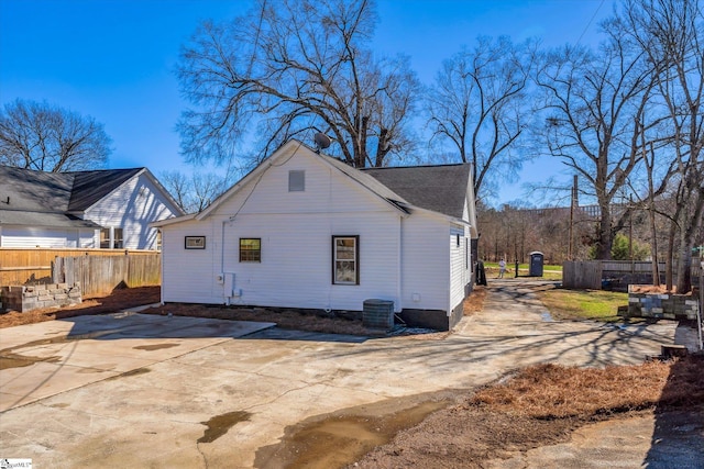 rear view of house with driveway, fence, and central air condition unit