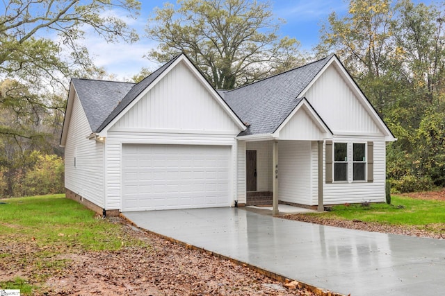 view of front of property with driveway, roof with shingles, an attached garage, a front lawn, and board and batten siding