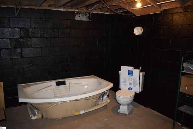 full bath featuring concrete floors, toilet, and a tub