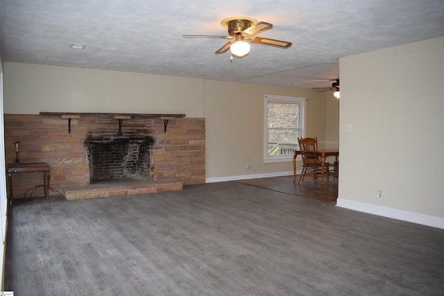 living area featuring baseboards, ceiling fan, wood finished floors, a textured ceiling, and a fireplace