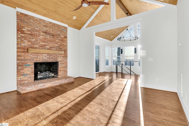 unfurnished living room featuring beam ceiling, a brick fireplace, wood finished floors, high vaulted ceiling, and wooden ceiling