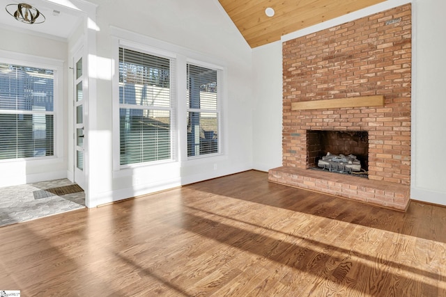 unfurnished living room with a fireplace, lofted ceiling, wood ceiling, wood finished floors, and baseboards