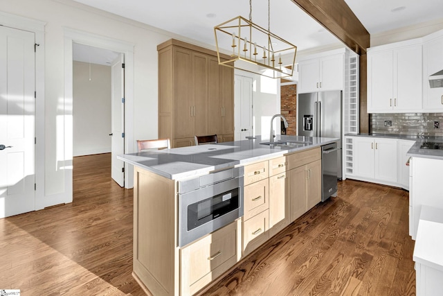 kitchen with appliances with stainless steel finishes, dark wood finished floors, a sink, and decorative backsplash