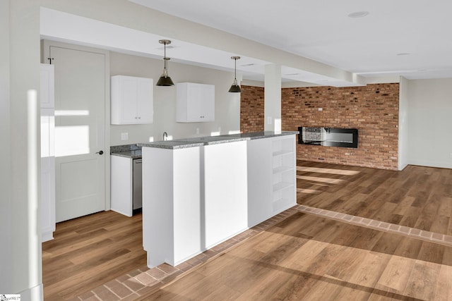 kitchen featuring a brick fireplace, stone countertops, white cabinets, and wood finished floors