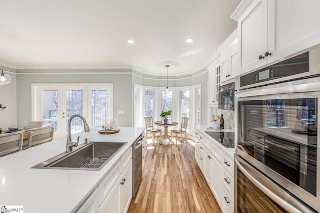 kitchen with appliances with stainless steel finishes, light countertops, crown molding, and a sink