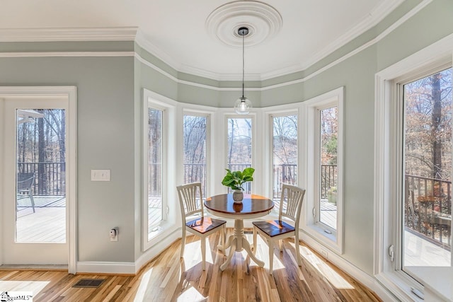 dining room with a healthy amount of sunlight, light wood-style floors, visible vents, and crown molding