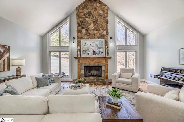 living area with a wealth of natural light, a fireplace, high vaulted ceiling, and wood finished floors