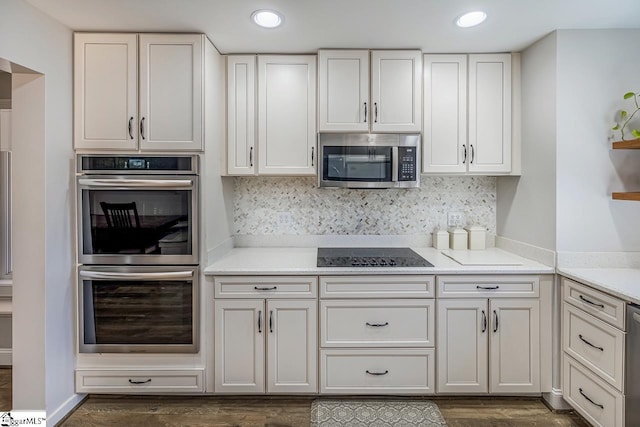 kitchen with appliances with stainless steel finishes, dark wood-style flooring, backsplash, and white cabinets