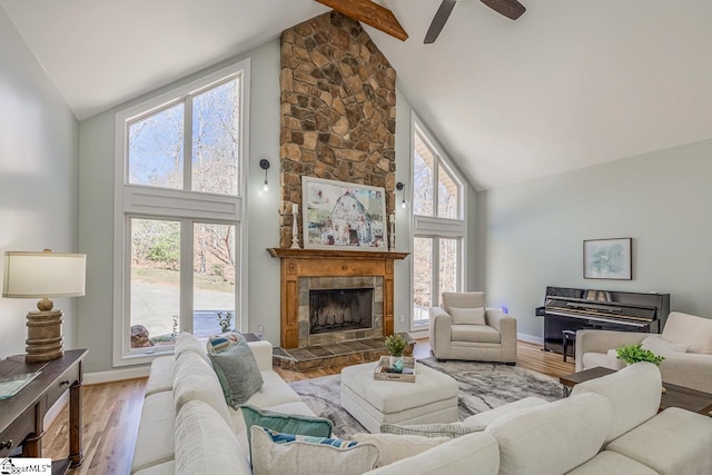 living area with high vaulted ceiling, a tile fireplace, beamed ceiling, and wood finished floors