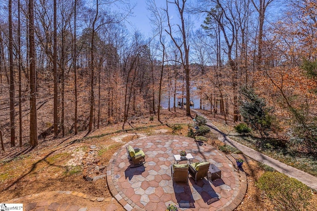 view of yard featuring a patio, outdoor dining area, and a wooded view