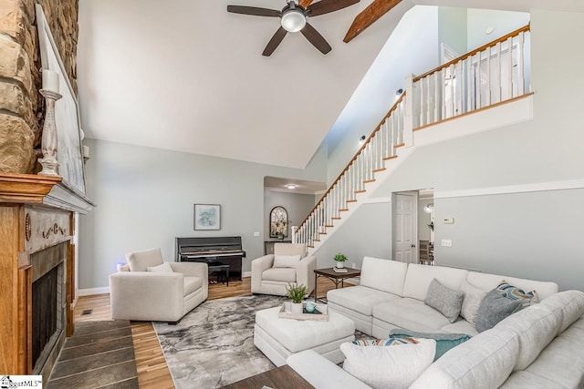 living area featuring dark wood-style flooring, a fireplace, a towering ceiling, baseboards, and stairway