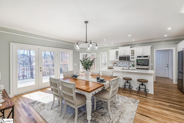 dining space with light wood-type flooring, a wealth of natural light, french doors, and ornamental molding