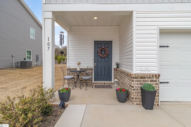 entrance to property featuring covered porch, brick siding, and central AC unit