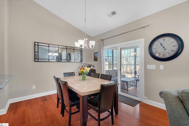 dining room featuring lofted ceiling, visible vents, an inviting chandelier, baseboards, and hardwood / wood-style flooring