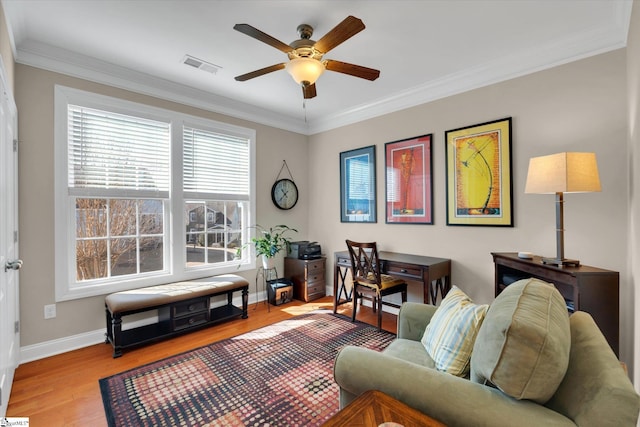 office area with wood finished floors, a ceiling fan, visible vents, baseboards, and ornamental molding