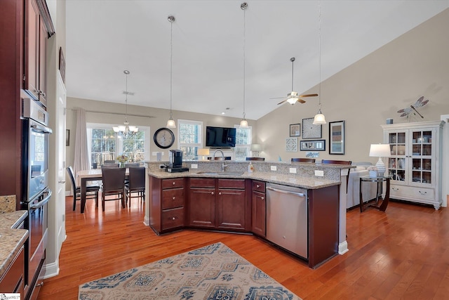 kitchen with appliances with stainless steel finishes, light wood-type flooring, a sink, and hanging light fixtures