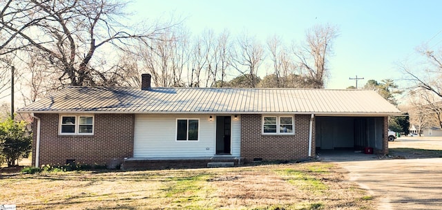 single story home featuring metal roof, brick siding, concrete driveway, a standing seam roof, and a chimney