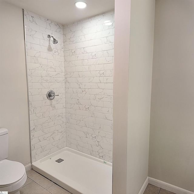 bathroom with toilet, a stall shower, baseboards, and tile patterned floors