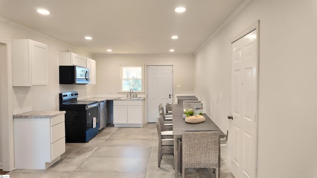 kitchen featuring light countertops, appliances with stainless steel finishes, a sink, and white cabinets