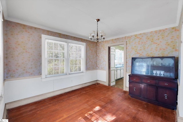 interior space with ornamental molding, wainscoting, wood finished floors, a chandelier, and wallpapered walls